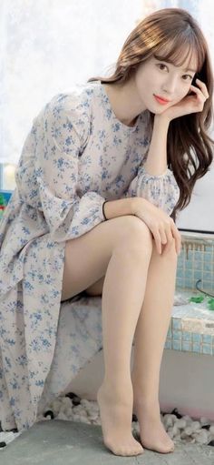 Woman in a floral dress with bare legs, sitting indoors