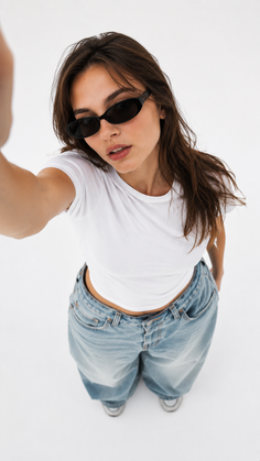 Woman in sunglasses and a white t-shirt taking a selfie from a high angle