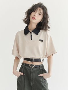 Woman with short hair wearing a cropped polo shirt and dark jeans