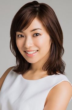 Woman with short brown hair and a white top smiling in a studio