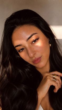 Woman with long black hair and gold jewelry in soft golden hour lighting