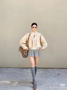 Woman in a pleated skirt and leopard print bag posing outdoors