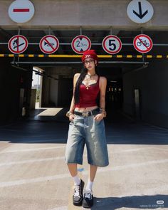 Woman in a red tank top and denim shorts standing in an urban setting