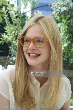Young woman with long blonde hair and decorative glasses smiling outdoors