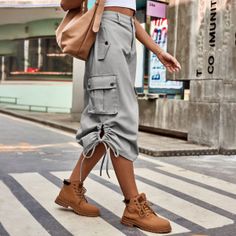 Person in a grey cargo skirt and brown boots walking on a pedestrian crossing