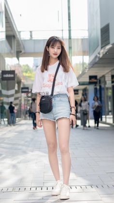 Young woman in denim shorts and a white t-shirt standing on a street