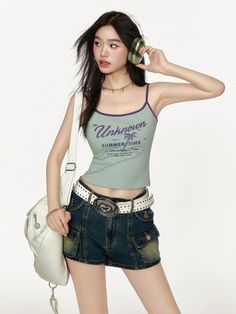 Woman in a crop top and denim shorts with headphones and a white bag