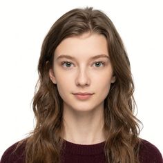 Young woman with long wavy hair and green eyes wearing a maroon sweater