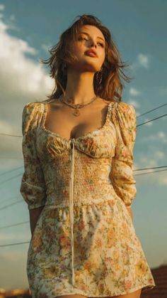 Woman in a floral dress with cleavage, looking up at golden hour