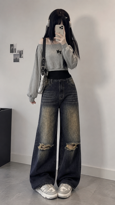 Person with long black hair wearing an off-shoulder top and ripped wide-leg jeans