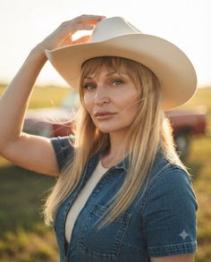 Woman in a cowboy hat and denim shirt outdoors at golden hour