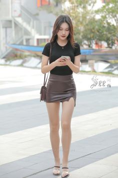 Woman in a black t-shirt and brown mini skirt walking outdoors