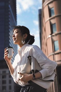 Woman in a white shirt holding a coffee cup in a city setting