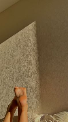 Feet with crossed legs against a textured wall with sunlight