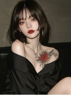 Woman with short dark hair and a red flower tattoo wearing an off-shoulder black shirt