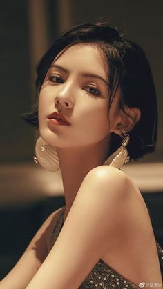 Woman with short black hair and large earrings in dramatic lighting