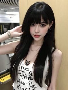 Woman with long black hair and bangs wearing a white tank top and jewelry