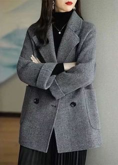 Woman in a gray coat and black turtleneck with arms crossed
