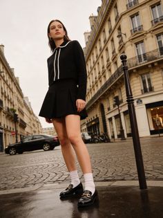 Woman in a black skirt and top standing on a cobblestone street