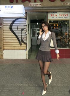 Woman in a mini skirt and tights walking on a street while on the phone