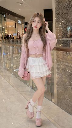 Woman in a pink top and white lace skirt with a pink cardigan indoors