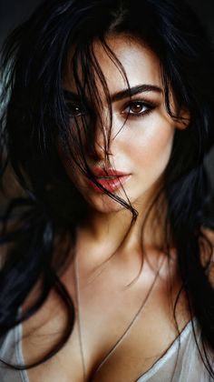 Woman with dark, wet hair covering part of her face, wearing a sheer top