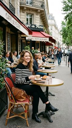 Woman smiling at an outdoor cafe with other patrons and a street in the background