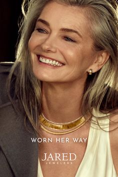 Woman with long gray hair wearing gold jewelry and smiling