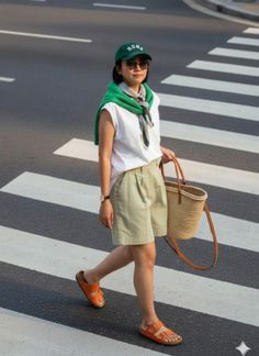 Woman in a green cap and shorts crossing a street