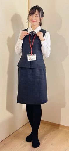 Woman in business attire with an ID badge, standing indoors