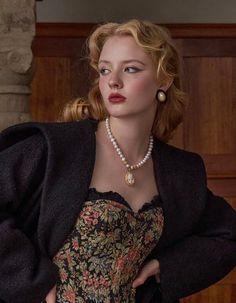 Woman with blonde wavy hair wearing a floral corset and pearl necklace