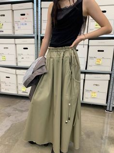 Person in a long skirt and black tank top standing in a storage room