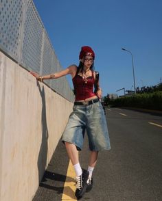 Woman in a red beanie and denim shorts posing on a street