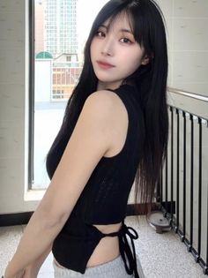 Woman with long black hair in a black top with exposed back
