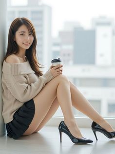 Woman in an off-shoulder sweater and mini skirt holding a coffee cup indoors