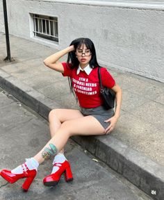 Woman with long black hair and glasses sitting on a street curb