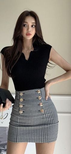 Woman with long hair wearing a black top and houndstooth mini skirt