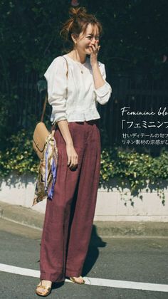 Woman in a white blouse and wide-leg pants laughing outdoors