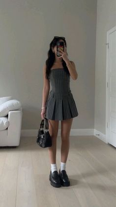 Woman in a pinstripe dress holding a black handbag, taking a mirror selfie