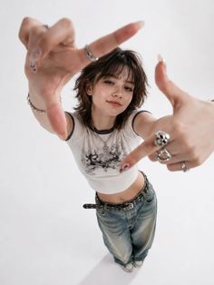 Young woman with shaggy hair in a crop top and baggy jeans, making a frame with her hands