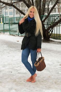 Woman with long blonde hair standing barefoot on snowy ground