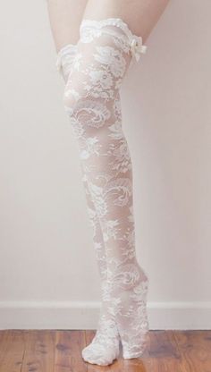 Legs wearing white lace thigh-high stockings with bows