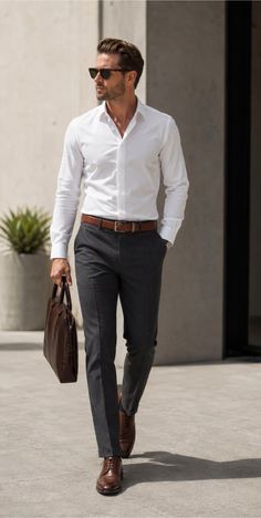 Man in a white shirt and suit pants walking outdoors with a briefcase