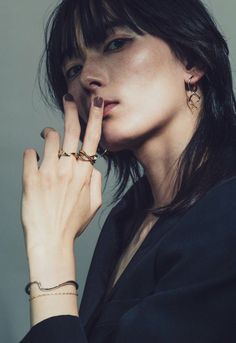 Woman with dark hair and freckles wearing a black blazer and gold jewelry