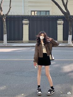 Woman in a brown jacket and black mini skirt posing on a street