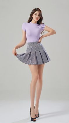 Woman in a purple top and pleated skirt posing in a studio