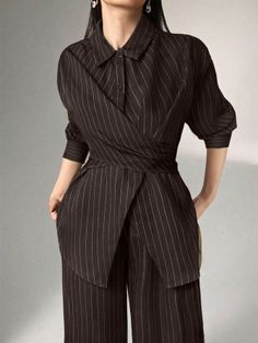 Woman in a dark pinstripe suit with a unique wrap-around top