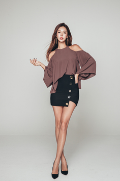 Woman in an off-shoulder top and mini skirt posing in a studio
