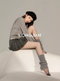 Woman in a beret, sweater, and pleated skirt with leg warmers in a studio