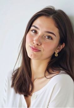 Woman with long brown hair and freckles wearing a white shirt and jewelry